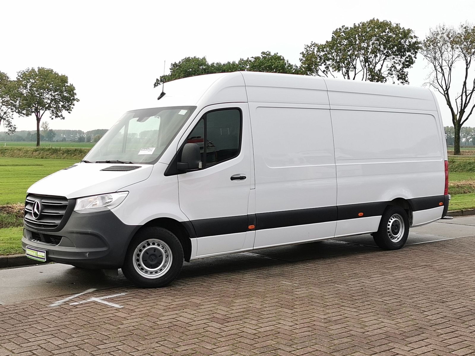 Photo of a larger white delivery vehicle driving on a city street